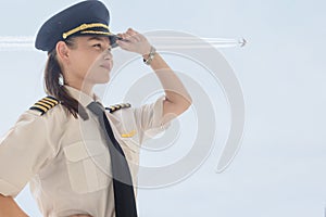 A female captain pilot standing next to an airplane at the airport