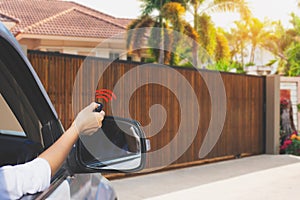 Female in car, hand using remote control to open the auto gate photo