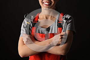 Female car mechanic with tools on black background, closeup