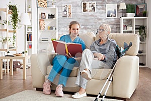 Female care giver reading a story from a book to a senior woman