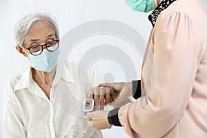 Female caregiver with fingertip pulse oximeter,attached on finger of elderly,health check,measuring oxygen saturation level and
