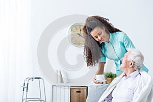 Female caregiver serving afternoon tea to patient