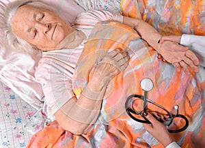 Female caretaker checking pulse of old woman photo