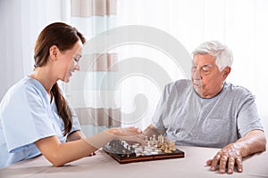 Female Caretaker Playing Chess With Senior Man photo