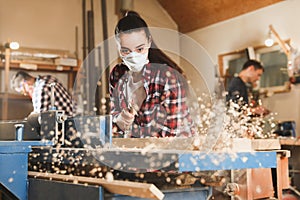 Female carpenter cleaning surface planer with air blow gun