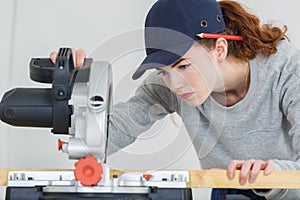 Female carpenter cutting wood with circular power saw