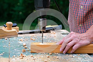 Female carpenter drilling wood plank, close-up view. Woodwork, DIY concept