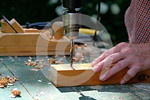 Female carpenter drilling wooden plank to make hole, close-up view. DIY, woodwork concept