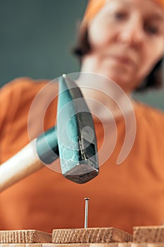 Female carpenter hammering nail into wooden crate