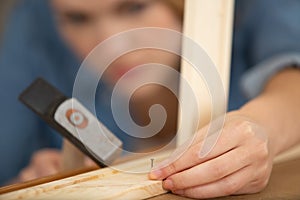 female carpenter hammering nail into wooden crate
