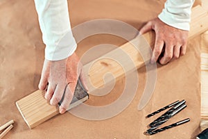 Female carpenter manually sanding wooden plank photo