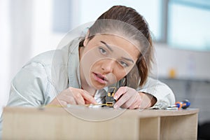 female carpenter measuring length wooden plank