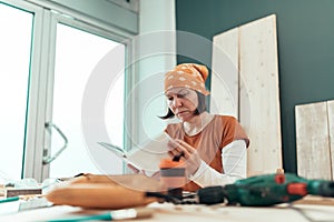 Female carpenter reading DIY project instruction manual photo