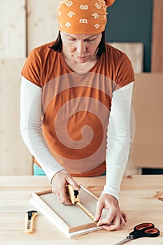 Female carpenter tape measuring picture frame in workshop