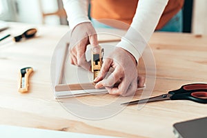 Female carpenter tape measuring picture frame in workshop