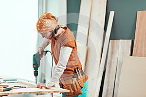 Female carpenter using electric drill photo