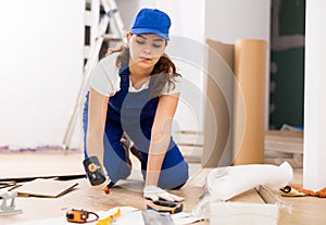 Female carpenter using rubber mallet to lay laminate flooring