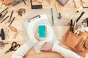 Female carpenter using smartphone, mock up screen top view