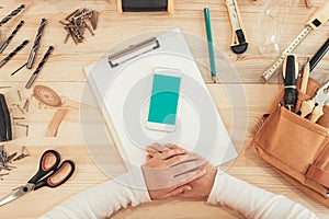 Female carpenter using smartphone, mock up screen top view