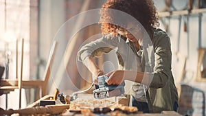 Female Carpenter Wearing Protective Safety Glasses and Using Electric Belt Sander to Work on a Wood