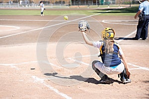 A female catcher crouching alone receiving the ball from the pitcher in a baseball game on the Turia River in Valencia