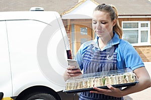 Female Caterer Delivering Tray Of Sandwiches To House Checking T