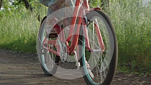 Female Caucasian feet pedaling bike outdoors on sunny summer day. Unrecognizable young woman in high-heels and dress