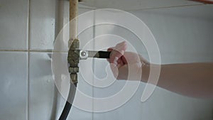 Female Caucasian hand turning off water pipe indoors at home. Unrecognizable Caucasian young woman shut off water supply