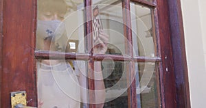 Female caucasian potter wearing face mask and apron changing close sign to open at entrance of potte