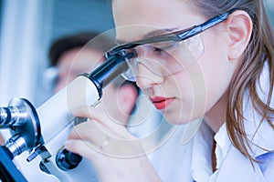 Female caucasian scientist wearing protective glasses l in laboratory