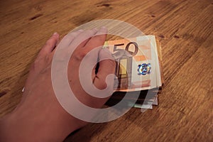 A female caucasian woman holding a hand of a stack of 50 euro banknotes