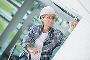 Female cctv installer setting security camera at office