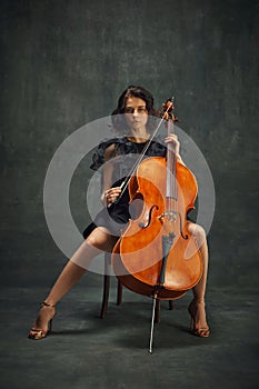 Female celloist sitting with cello on dark green background. Book cover for musician& x27;s memoir, emphasizing personal photo