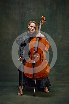 Female celloist sitting with cello on dark green background. Cover for upcoming music events, solo performance of