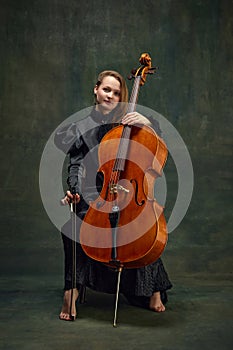 Female celloist sitting with cello on dark green background. Cover for upcoming music events, solo performance of photo