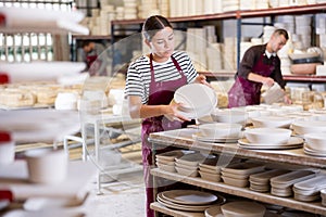 Female ceramicist placing handcrafted plates on storage racks photo