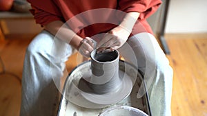 Female ceramist shaping and forming clay into shape on pottery wheel, making ceramics at home