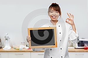 female chef with chalkboard showing ok on kitchen