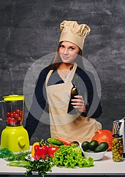 Female chef cook holds bottle with oil.
