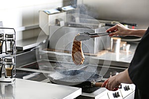 Female chef cooking chicken fillet on stove in restaurant  kitchen