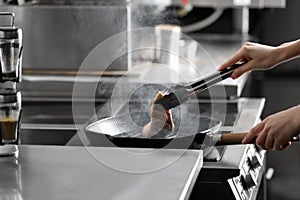 Female chef cooking chicken fillet on stove in restaurant  kitchen