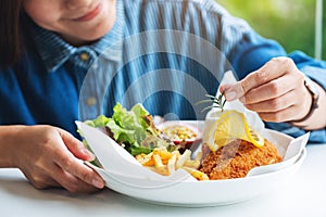 A female chef cooking and decorating a dish of fish and chips