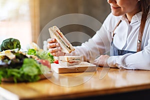 A female chef cooking and eating a whole wheat sandwich in kitchen