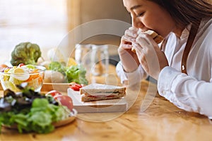 A female chef cooking and eating a whole wheat sandwich in kitchen