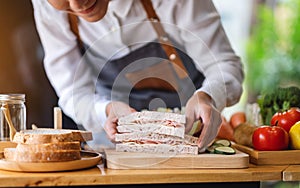 A female chef cooking and holding a piece of whole wheat ham cheese sandwich in kitchen