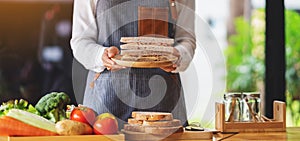 a female chef cooking and holding a plate of whole wheat ham cheese sandwich in kitchen