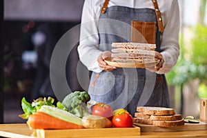 a female chef cooking and holding a plate of whole wheat ham cheese sandwich in kitchen