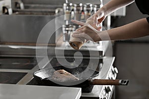 Female chef cooking meat on stove in restaurant kitchen