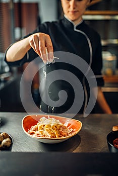 Chef cooking pasta with cheese in a bowl
