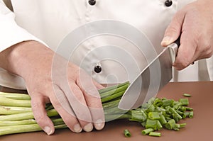 Female chef cuts spring onion with a large knife